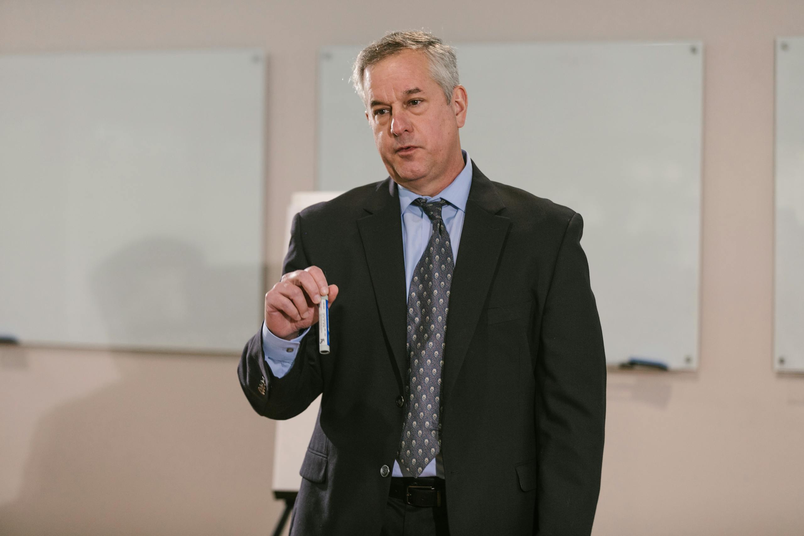 Businessman in suit presenting in office setting, emphasizing leadership and confidence.